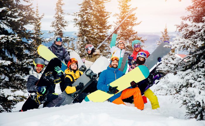 Concept travel ski resort with group of friends. Team winter sports skiers and snowboarders with sunset.