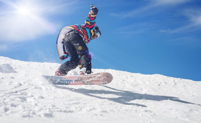 Freerider snowboarder rolls and rides his snowboard on extreme gradient downhill. Winter mountain freeride